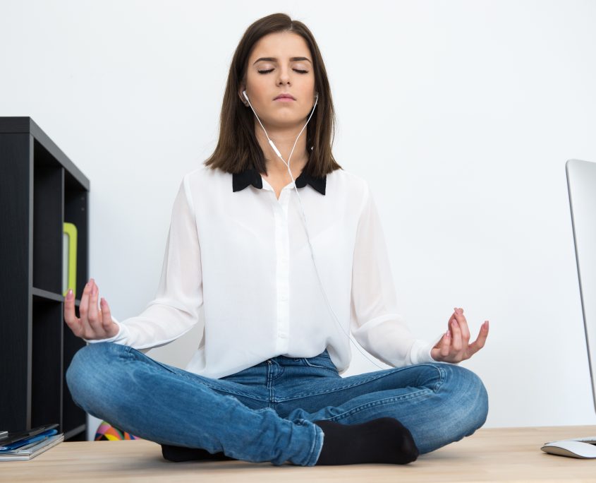 Young woman meditating at the table in office